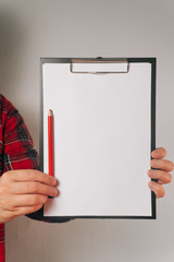 man holds in his hands a white sheet of paper in a folder next to a simple pencil. Copy space concept. an object