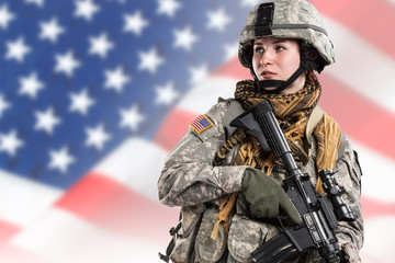 Female in US Army soldier (ISAF) with rifle. Flag of USA on background