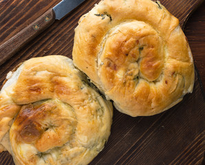 Traditional Balkan food, Serbian burek with cheese ans spinach, banica, Turkish borek on wood plate top view.
