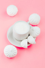Cup of milk and white marshmallows on pink background close up