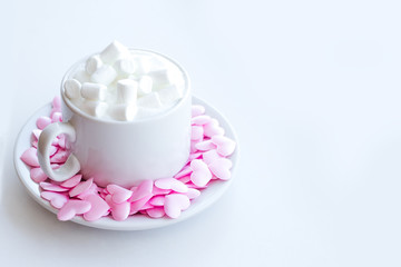 Cappuccino cup decorated with pink hearts and marshmallows on white background