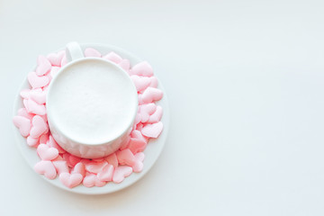 Cappuccino cup decorated with pink hearts and marshmallows on white background