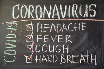 Coronavirus symptoms. Outbreak Warning. written white chalk on blackboard in connection with epidemic of coronavirus worldwide.