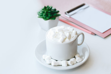 Cappuccino with marshmallows and tablet folder on white background