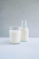 Glass of milk with bottle of milk on gray background. Healthy vegetarian food and drink concept.