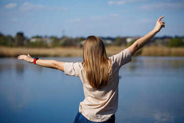 Girl dancing near the lake, sunny weather. A young woman rejoices in life, dances and sings. She has a good mood and a smile on her face.