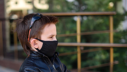 A boy in black mask  is upset that he cannot get out because of the coronavirus Looks very depressed. Psychological state of the child