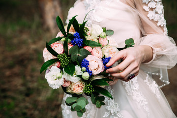 Wedding bouquet of roses, carnations, peonies gently pink in the hands of the bride