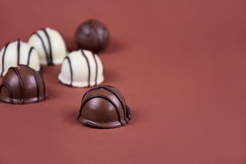 Chocolate pralines on a brown background stock images. Dark and white chocolate candies frame. Chocolate candies on a brown background with copy space for text stock images. Chocolate pralines border
