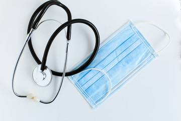 Medical supplies on a white background top view, stethoscope and medical face mask in blue