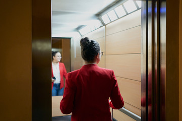 A woman in red blazer entering a hotel elevator