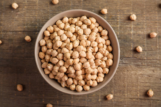 Chickpeas in ceramic bowl on wooden background.