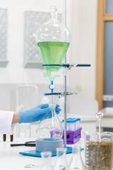 Hand operating with blue liquid in separatory funnel