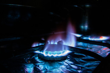Blue natural gas burns on the hob at night