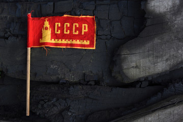 The old small flag of the Soviet Union on burnt boards. symbol of the Soviet Union. burnt past. concept