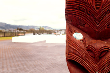 Maori Figur vor einem Friedhof