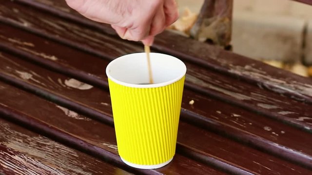 Stirring Hot Drink in Yellow Paper Cup, Coffee To Go Concept