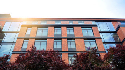 Modern apartment buildings on a sunny day with a blue sky. Facade of a modern apartment building. Glass surface with sunlight.