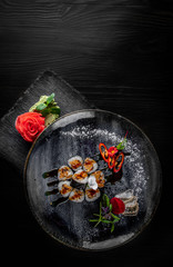 Obraz na płótnie Canvas sushi roll with eel and rice in plate on black wooden table background