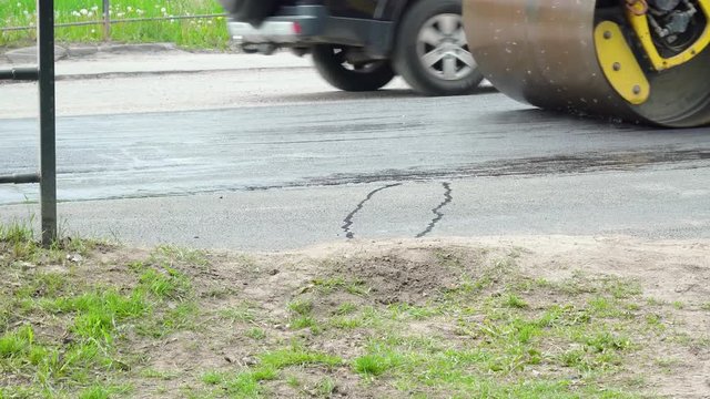 Yellow road roller rides on a road while laying asphalt. Building new road