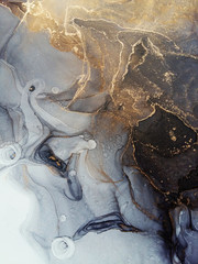 Luxury abstract fluid art painting in alcohol ink technique, mixture of black and grey paints.  Imitation of marble stone cut, glowing golden veins. Tender and dreamy design. 