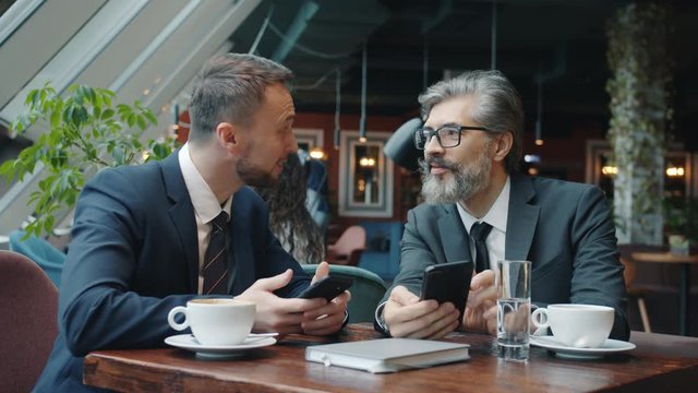 Cheerful colleagues managers in formalwear are talking and laughing during lunch break in cafe relaxing after work. Business people and communication concept.