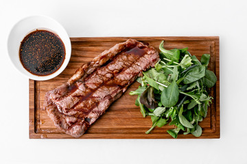 Grilled steak with sauce and lettuce.