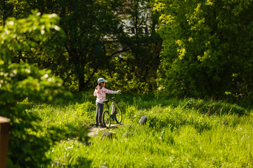 Obraz premium Portrait of a little girl on a bicycle in summer park outdoors