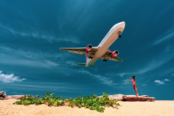 Young beautiful woman have fun on the beach watching the danger landing huge plane at Phuket Airport over Mai Khao Beach in Thailand