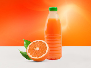 Template of a plastic bottle of orange juice on a light background. Nearby juicy orange with green leaves lies
