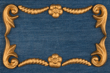Frame made of gold-painted plaster molding lying on denim. Copy space. Top view.