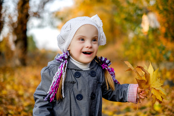Down syndrome schild smiling in autumn forest, happy despite all problems, awareness