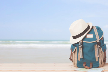 Backpack and hat with map on the beach view background.