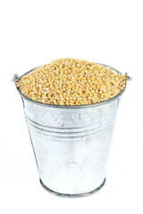 Full bucket of millet grains on a white background.