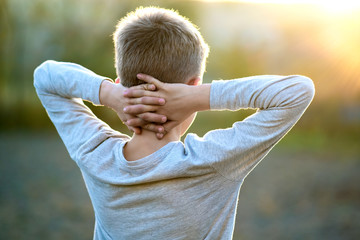 Child boy standing outdoors on summer sunny day enjoying warm weather outside. Rest and wellness concept.