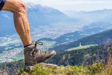 close up of a leather hiking shoe and the calf muscles of a man on a sunny day at Ziller Valley in the austrian alps