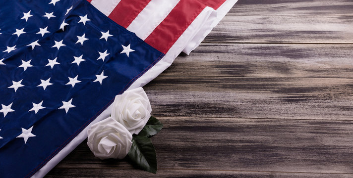  Vintage red, white, and blue American flag with white roses on a wood background for Memorial day, 4th of July, Flag Day  , Veteran's day, or Independence Day. 