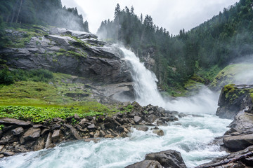 view of the Krimml Waterfalls from below on a wet and cloudy day in Austria. Majestic stream flowing at the highest waterfall of europe