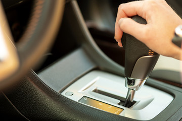Close up of woman driver holding her hand on automatic gear shift stick driving as car.