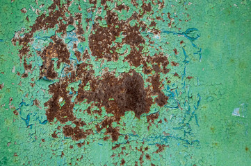 metal plate, painted with green paint, from which rust is visible