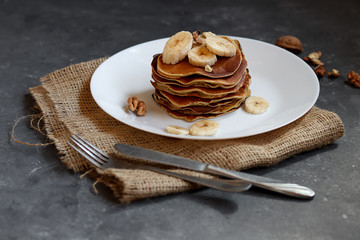 Protein pancakes with banana and walnut on a dark background.