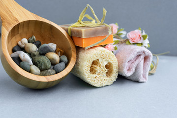 The bath accessories for spa treatments towel,  washcloth,  soap, stones on grey background.  Spa salon concept.