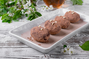 Kartoshka cake on the ceramic platter on the white wooden table. Russian potato-shaped dessert