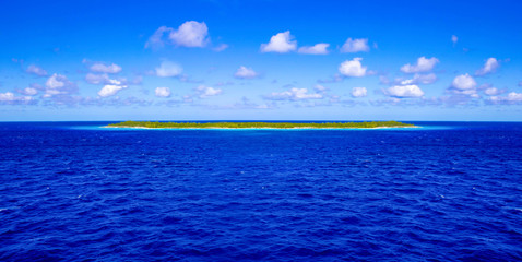 Small uninhabited tropical island in blue ocean