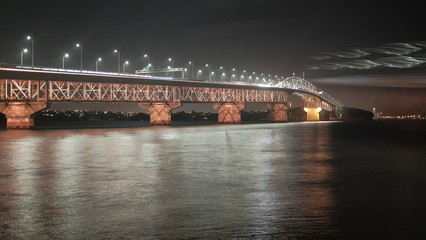 Auckland bridge with the night light up reflection on Auckland Bay water at Auckland city, New Zealand 