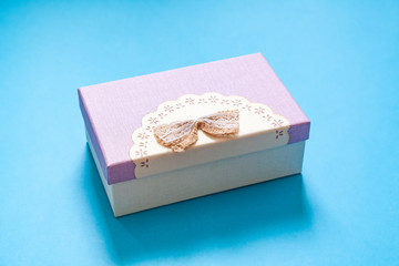 cardboard gift box in purple color scheme with a bow on a blue background