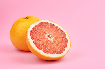 Fresh whole and cut red grapefruit fruits on pink background