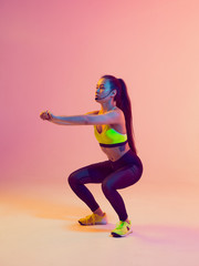 Fototapeta na wymiar Athletic cool girl trainer teaches group crossfit and work out online training on a bright neon background.