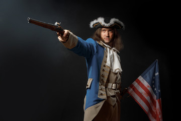 Man in form of officer of United States Revolutionary War with a flag and gun. July 4th,...
