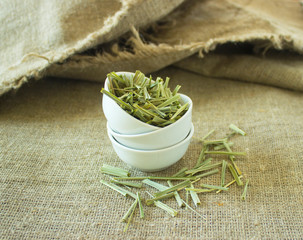 Lemon Grass (Cymbopogon citratus, Capim Limao, Santo). Pile of dried Lemongrass in white bowl. Dried sprigs of natural lemongrass, dried herb, herbal medicine. Selective focus, closeup